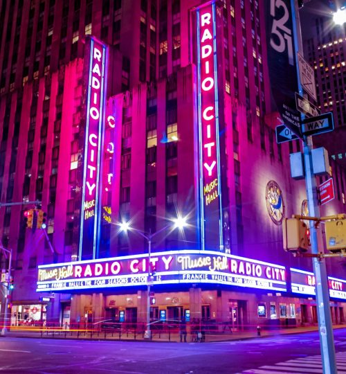 Illuminated facade of Radio City Music Hall glowing in neon at night in New York City.